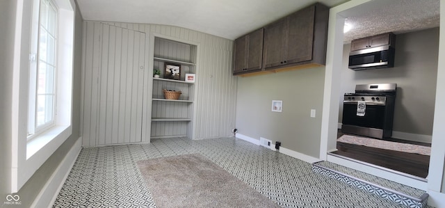clothes washing area with cabinet space, baseboards, hookup for a washing machine, and wood walls