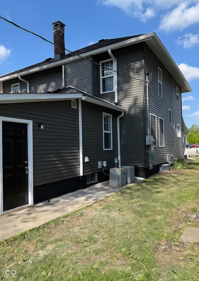 view of home's exterior with a chimney, central air condition unit, and a lawn