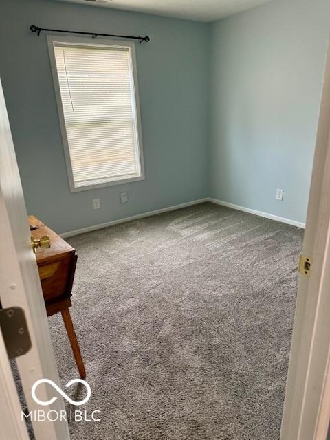 empty room featuring carpet floors and baseboards
