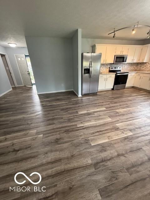 kitchen with dark wood finished floors, backsplash, white cabinets, and stainless steel appliances