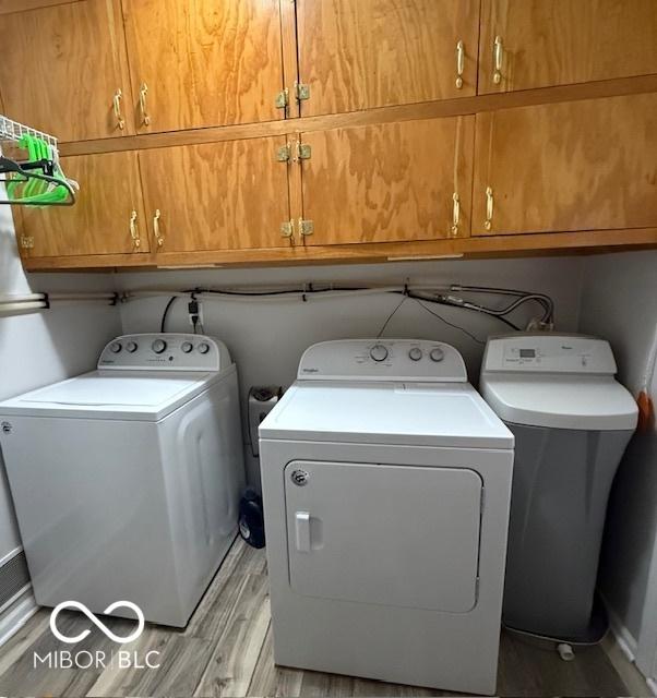 laundry room featuring light wood finished floors, cabinet space, and washer and dryer