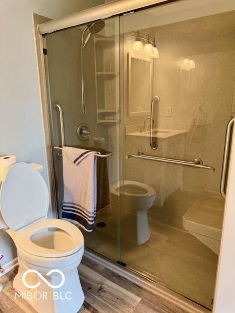 bathroom featuring a stall shower, toilet, and wood finished floors
