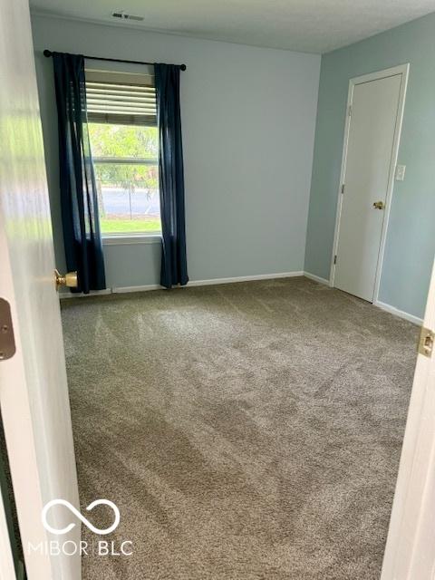 unfurnished room featuring carpet floors, baseboards, and visible vents