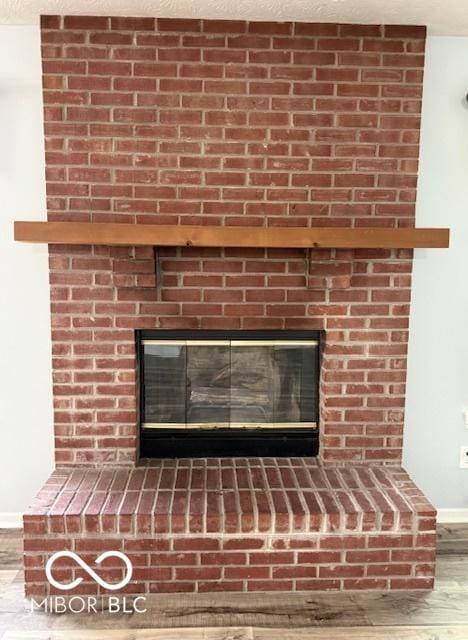 interior details featuring baseboards, a fireplace, a textured ceiling, and wood finished floors