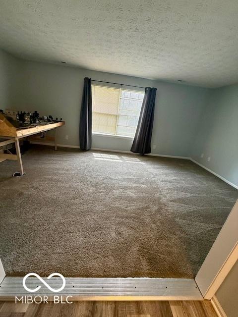carpeted empty room with a textured ceiling and baseboards