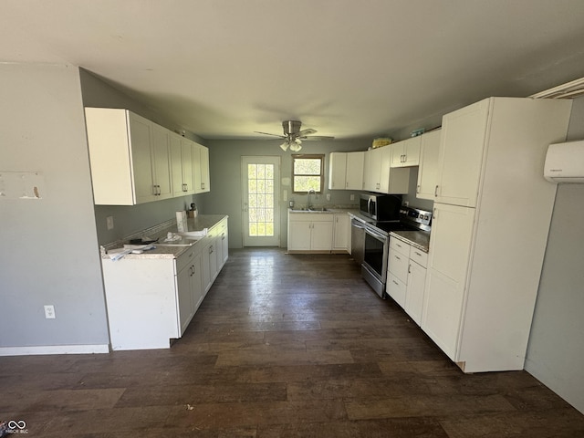 kitchen featuring ceiling fan, appliances with stainless steel finishes, a sink, white cabinets, and dark wood-type flooring