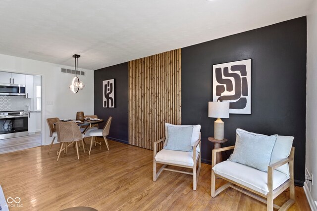 sitting room featuring visible vents, baseboards, light wood finished floors, and a notable chandelier