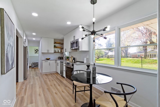 dining area featuring light wood finished floors, recessed lighting, a notable chandelier, and baseboards