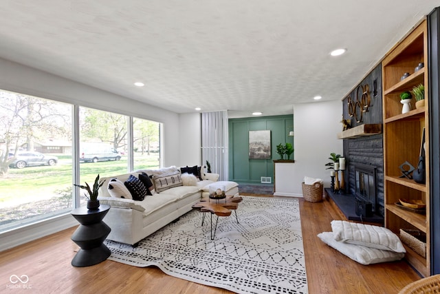 living room featuring baseboards, recessed lighting, wood finished floors, and a fireplace
