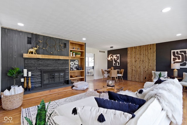 living area featuring visible vents, wood finished floors, an inviting chandelier, and an accent wall