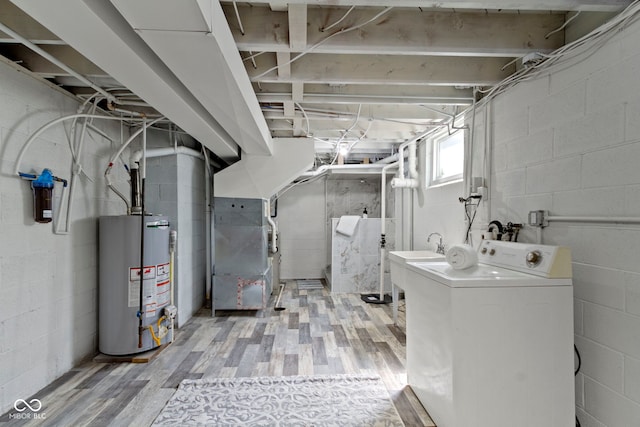 basement featuring water heater, heating unit, washer / dryer, and light wood-style flooring