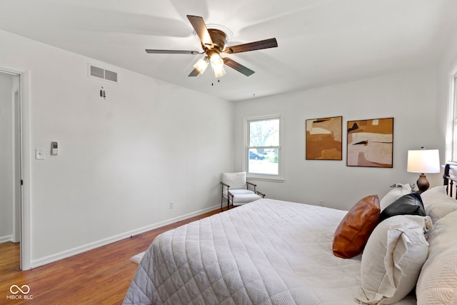 bedroom with visible vents, ceiling fan, wood finished floors, and baseboards
