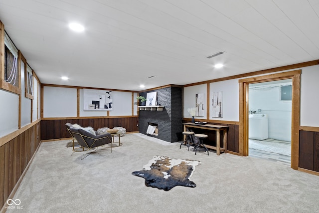 carpeted living area with wooden walls, a wainscoted wall, visible vents, and washer / dryer