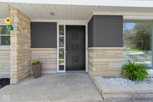 property entrance featuring a porch and stone siding