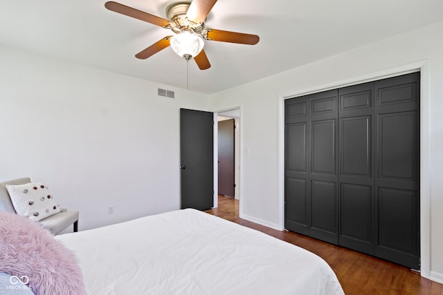 bedroom featuring a closet, a ceiling fan, visible vents, baseboards, and wood finished floors