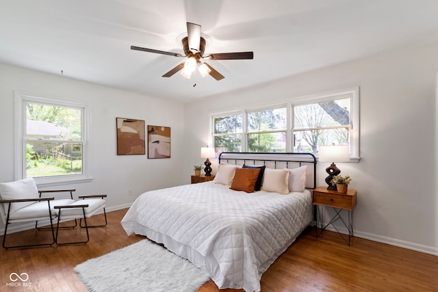 bedroom with baseboards, wood finished floors, ceiling fan, and multiple windows
