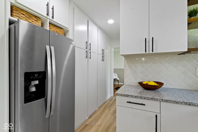 kitchen featuring light stone counters, decorative backsplash, light wood-style floors, white cabinetry, and stainless steel refrigerator with ice dispenser