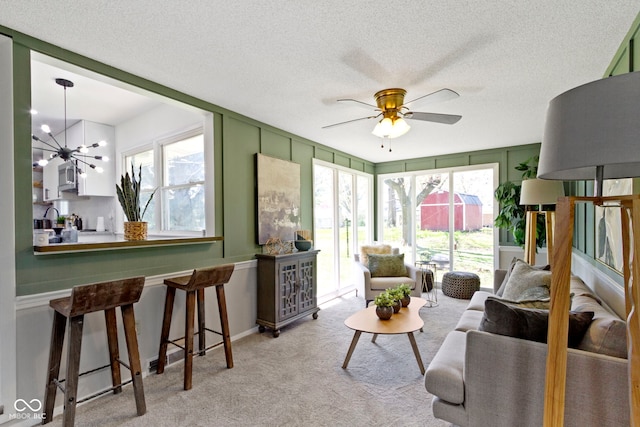 living area with a textured ceiling, a wealth of natural light, and carpet