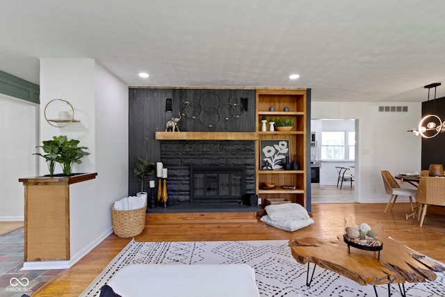 living area with a fireplace, recessed lighting, visible vents, and baseboards