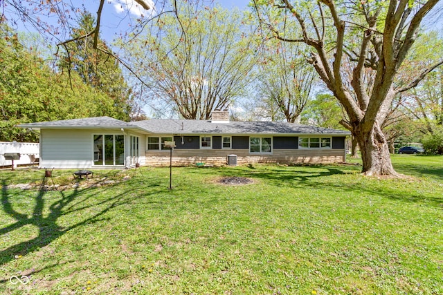 rear view of house with a chimney, fence, and a yard