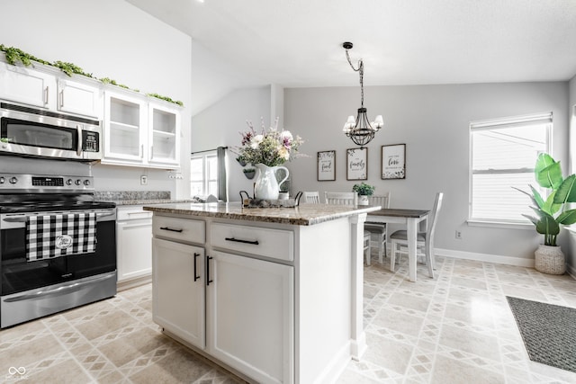 kitchen with white cabinets, light stone countertops, an inviting chandelier, stainless steel appliances, and vaulted ceiling