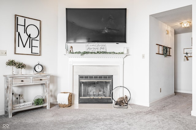 carpeted living area featuring baseboards and a fireplace with flush hearth