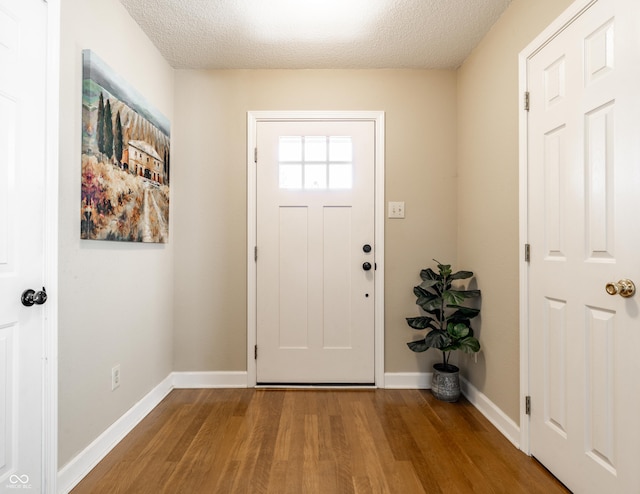 entrance foyer with a textured ceiling, baseboards, and wood finished floors