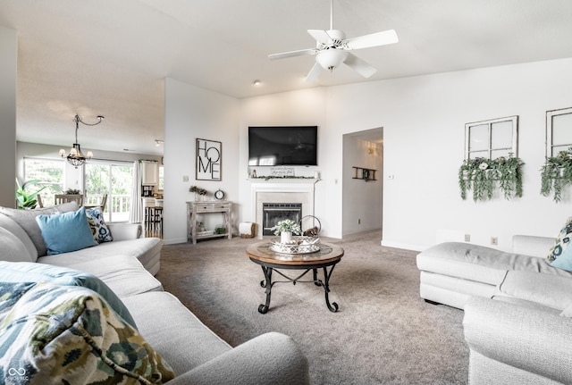 living room with baseboards, a glass covered fireplace, carpet, and ceiling fan with notable chandelier