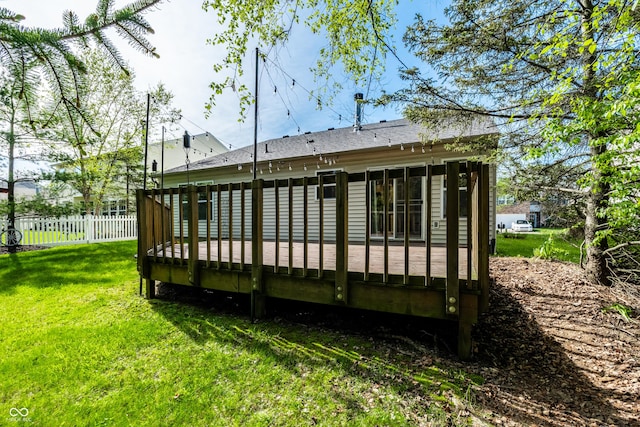 rear view of property with fence, a wooden deck, and a yard