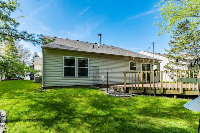 back of property featuring a lawn, a deck, and a shingled roof
