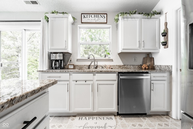 kitchen with a textured ceiling, dishwasher, a sink, light stone counters, and white cabinets