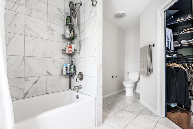 bathroom with toilet, shower / tub combo, marble finish floors, a spacious closet, and baseboards