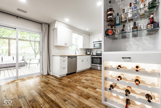 kitchen with appliances with stainless steel finishes, decorative backsplash, light wood-style floors, white cabinetry, and recessed lighting