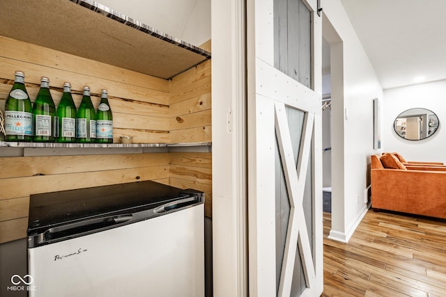kitchen with light wood-style flooring, a barn door, and baseboards