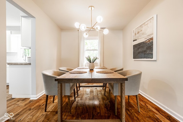 dining space with wood finished floors, a chandelier, and baseboards