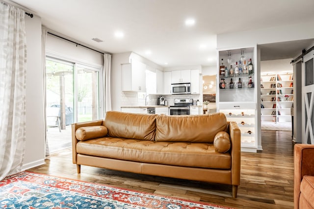 living room featuring a barn door, light wood-type flooring, and recessed lighting