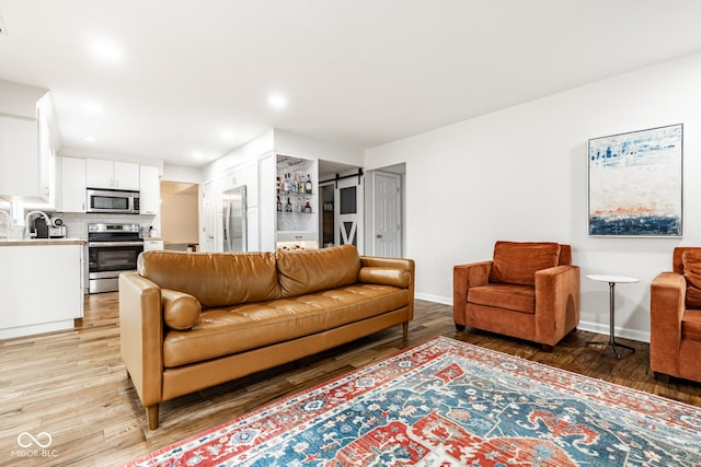living area featuring baseboards, light wood-type flooring, and recessed lighting