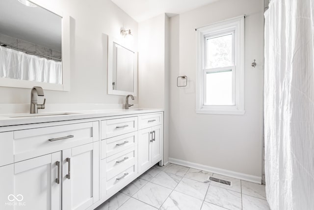 full bathroom with marble look tile flooring, double vanity, and baseboards