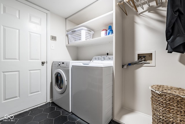 clothes washing area with washing machine and clothes dryer and dark tile patterned floors