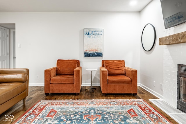 sitting room with wood finished floors, a fireplace, and baseboards
