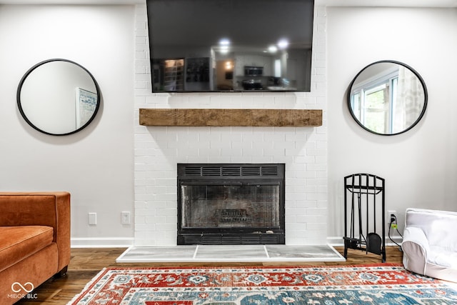 living area with wood finished floors, a fireplace, and baseboards
