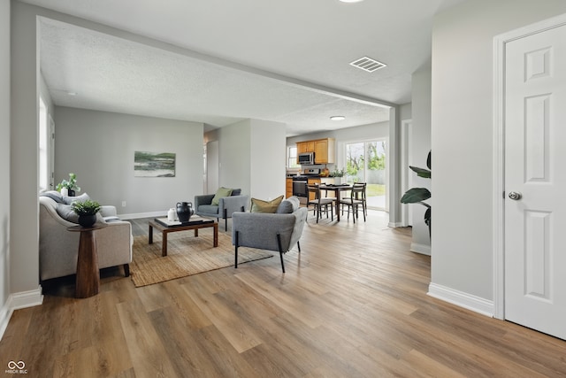 living room with baseboards, visible vents, and light wood finished floors