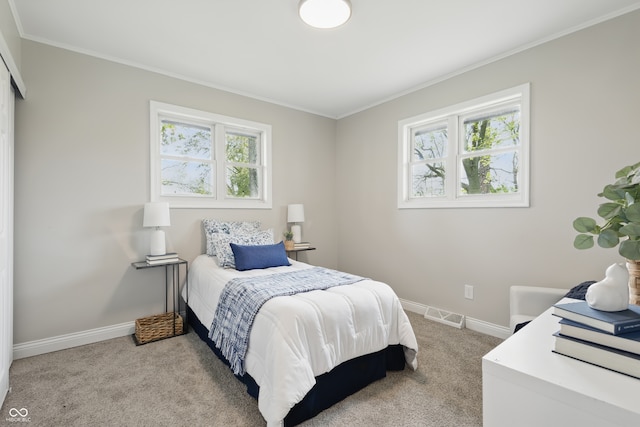 bedroom featuring light colored carpet, visible vents, ornamental molding, and baseboards