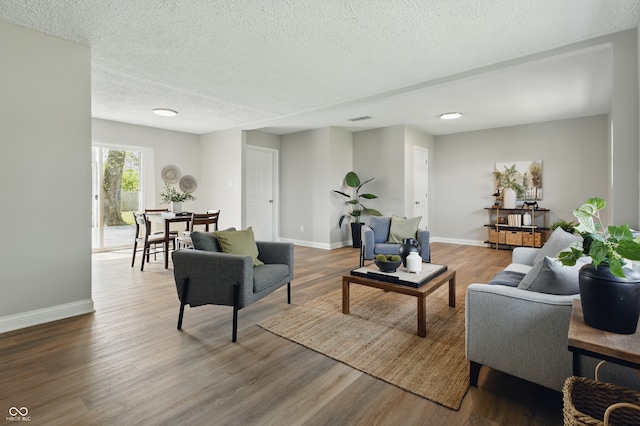 living room featuring baseboards, visible vents, wood finished floors, and a textured ceiling