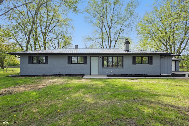 view of front facade with a front lawn, a chimney, and brick siding