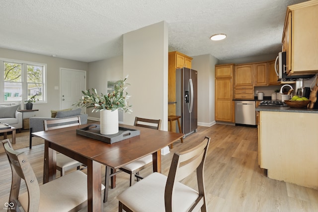 dining area with a textured ceiling, light wood-type flooring, and baseboards