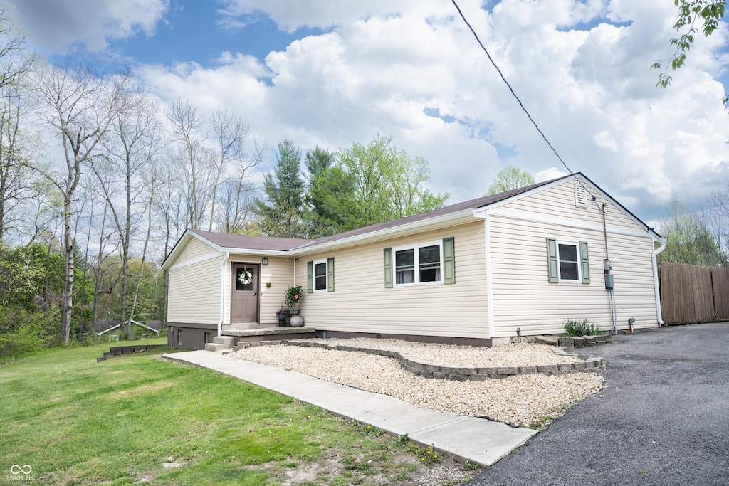 ranch-style house with a front yard, driveway, and fence