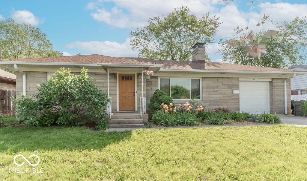 1021 N Bolton Ave, Indianapolis, IN 46219 - single story home with a front lawn, a chimney, an attached garage, driveway, and stone siding