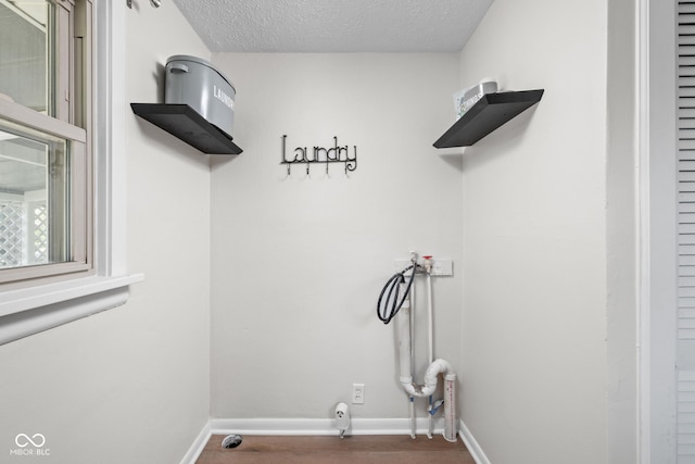 laundry room with a textured ceiling, washer hookup, and baseboards
