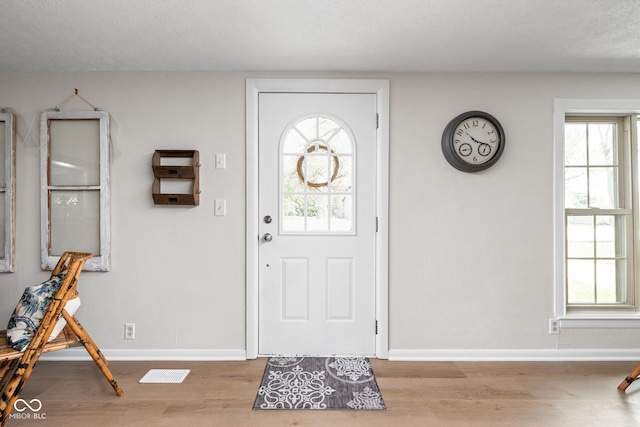foyer entrance with wood finished floors and baseboards